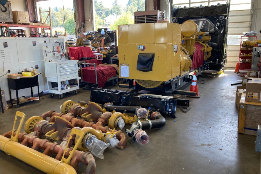 A partially disassembled large Cat generator set with new components laid out in the Eugene Power Systems shop