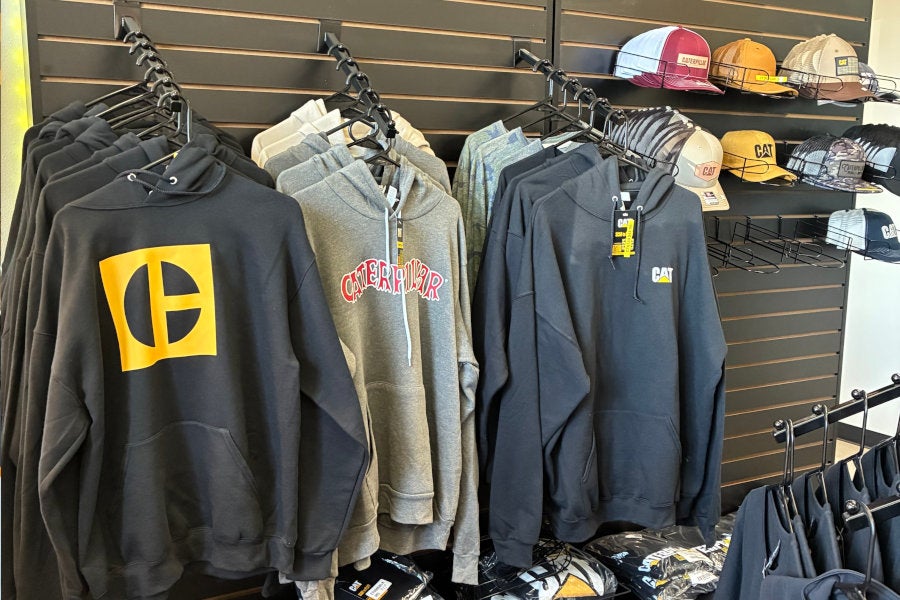A retail display of Cat branded hats, hoodies, shirts, and gifts