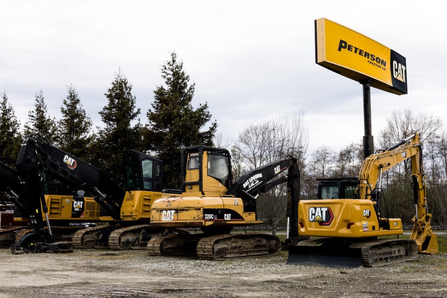 New and used Cat excavators and forestry machines parked under a Peterson Cat sign