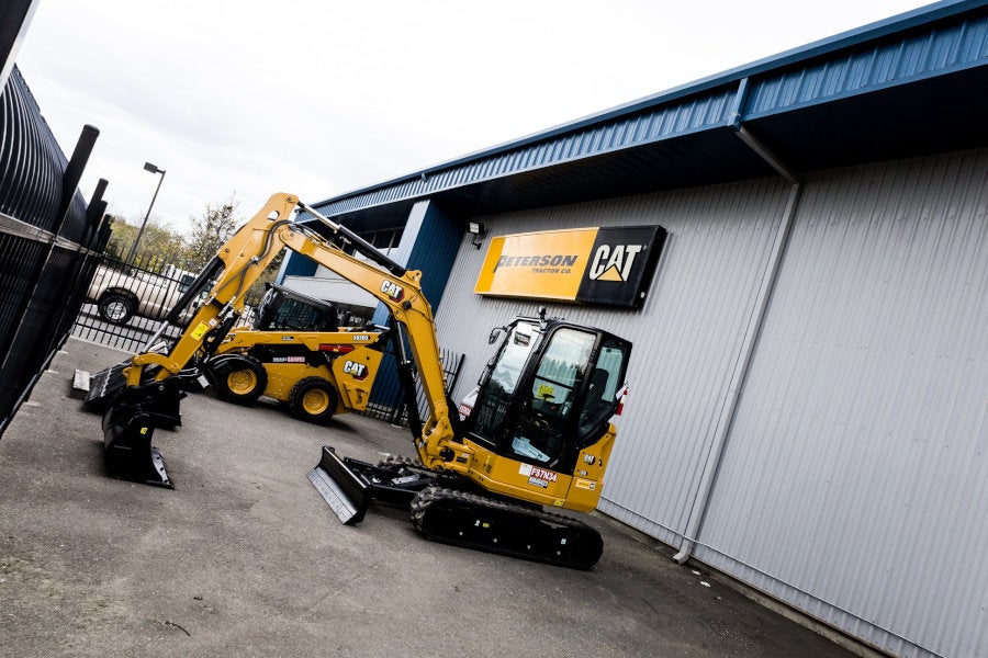 A new Cat mini excavator and a new Cat skid steer parked under a Peterson Cat sign
