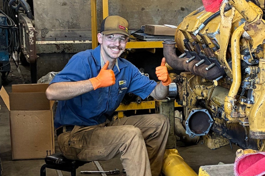 A Peterson Cat technician wearing safety glasses and gloves while servicing an engine removed from a Cat 988F Wheel Loader