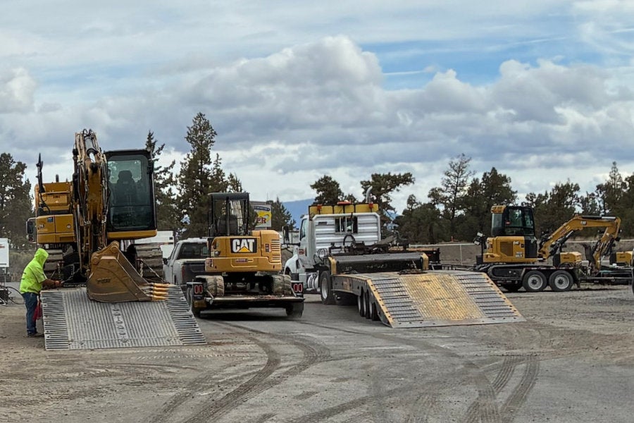 Three Cat Rentals excavators of different sizes getting loaded onto equipment hauling trailers at the Redmond store