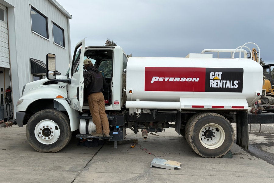 A Peterson employee is cleaning inside the cab of a 2,000 gallon Cat Rentals water truck