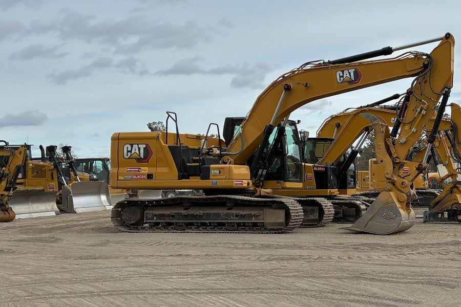 A row of Cat medium and mini excavators with hydraulic work tools in front of a row of Cat Rentals dozers