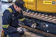 Peterson Technician greasing the tracks of a Cat mini excavator