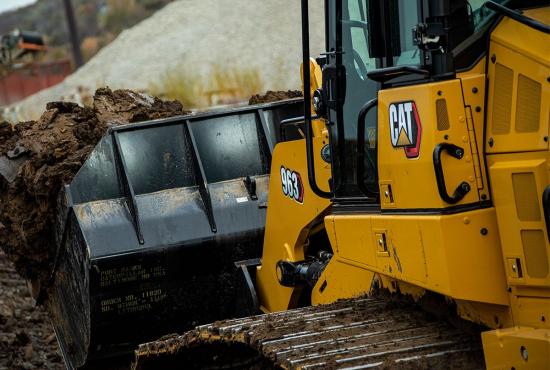Cat crawler loader carries a heavy bucket of dirt