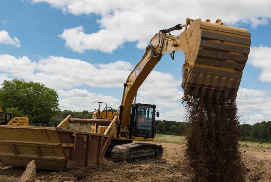 323 Hydraulic Excavator filling in a dirt hole