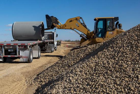 973 track loader with forks unloading concrete pipe