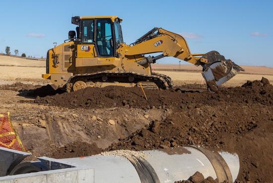 The 973 crawler loader works with excavators on a sewer installation project