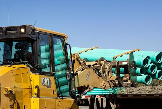 Cat 953 track loader fitted with forks to carry pipe