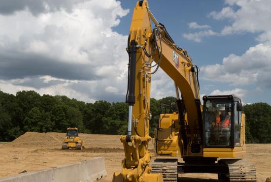 325 Hydraulic Excavator digging near a barrier