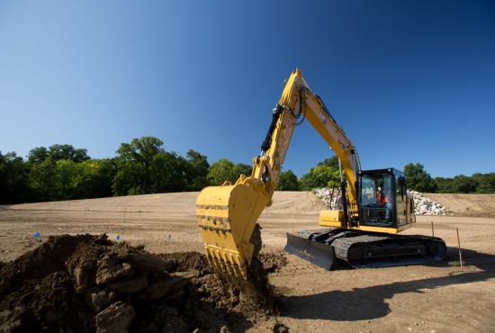 Cat 313 hydraulic excavator digging with a bucket at a construction site.
