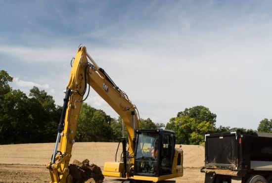 Cat 313 hydraulic excavator digging a trench at a construction site.